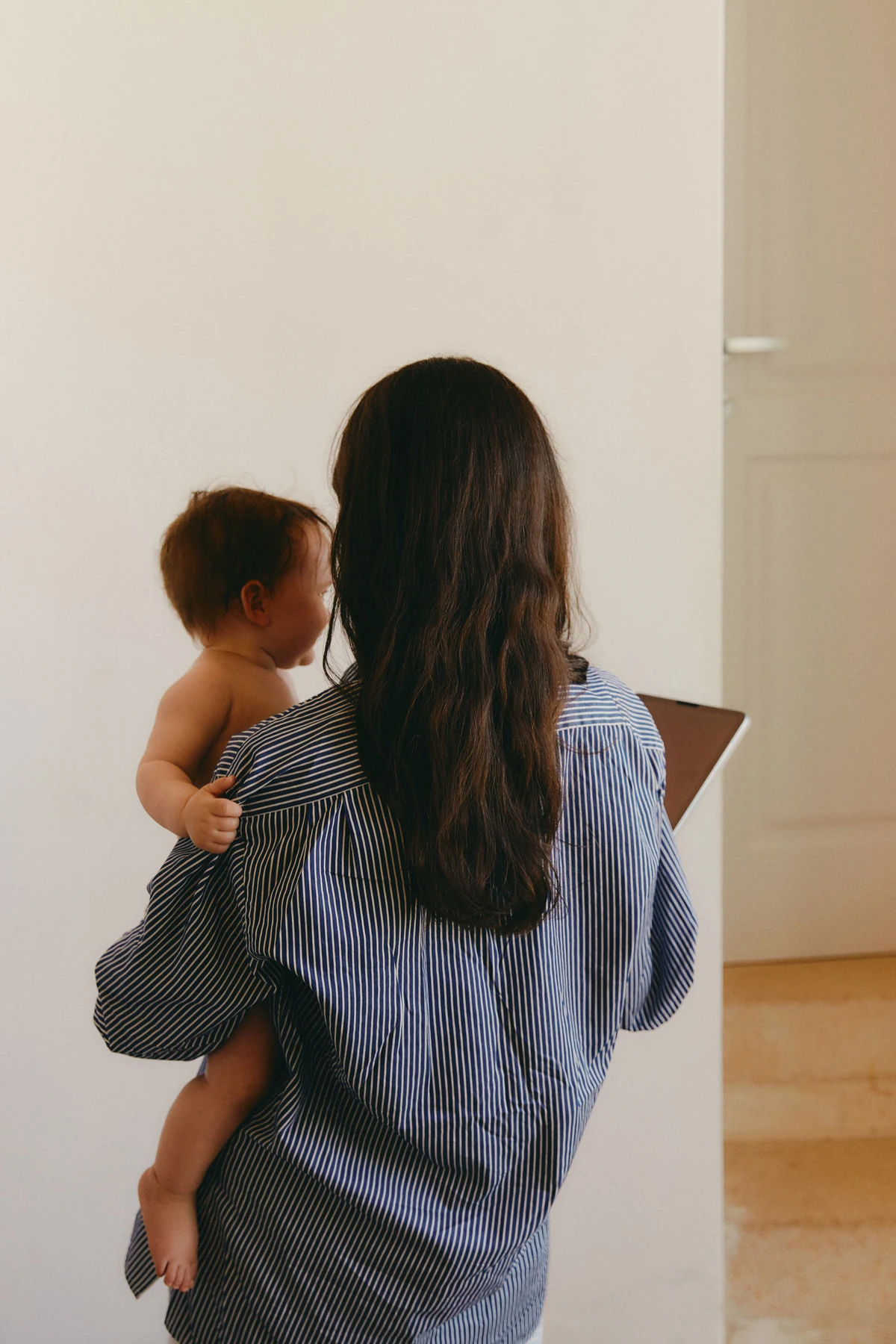A parent at home, carrying their child down the hall